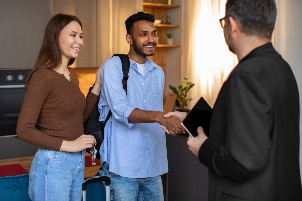 Host greeting traveling guests with a handshake and keys in a vacation rental
